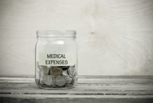 Label on a glass jar with the inscription - medical expenses. Glass jar with coins. Financial concept on wooden background