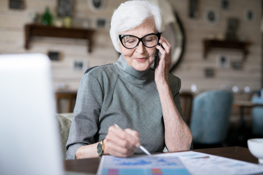 Elder lady with white haired planning her work while talking on cellphone