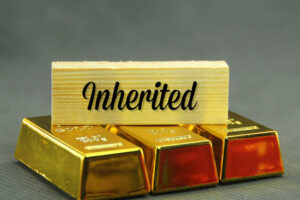 three gold nuggets and a wooden board with the word inherited concept