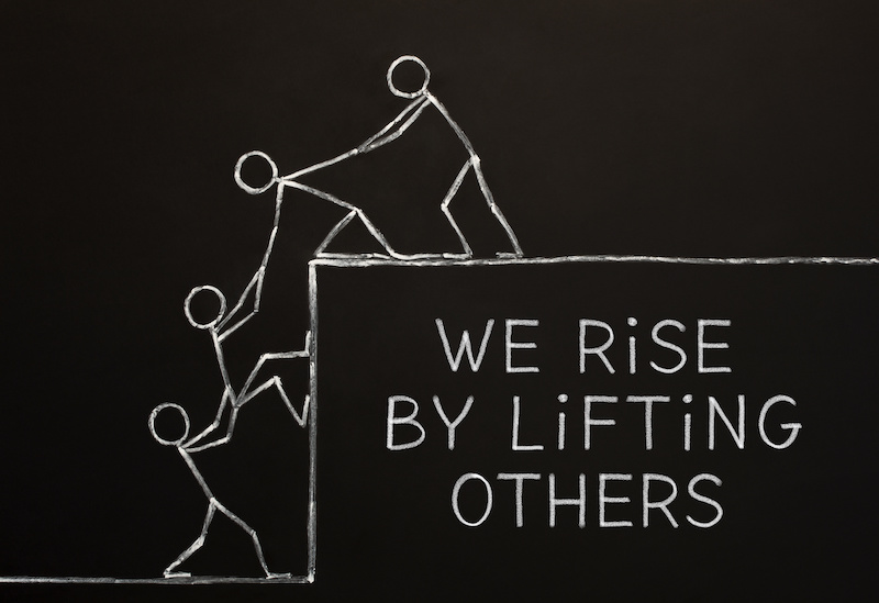 Quote We Rise By Lifting Others handdrawn on altruism, kindness, unselfishness, or teamwork concept drawn with chalk on blackboard.