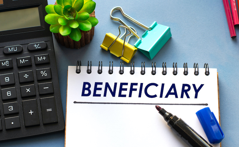 BENEFICIARY word is written in a notebook with a marker, calculator, clamps and cactus. Business concept End of Life