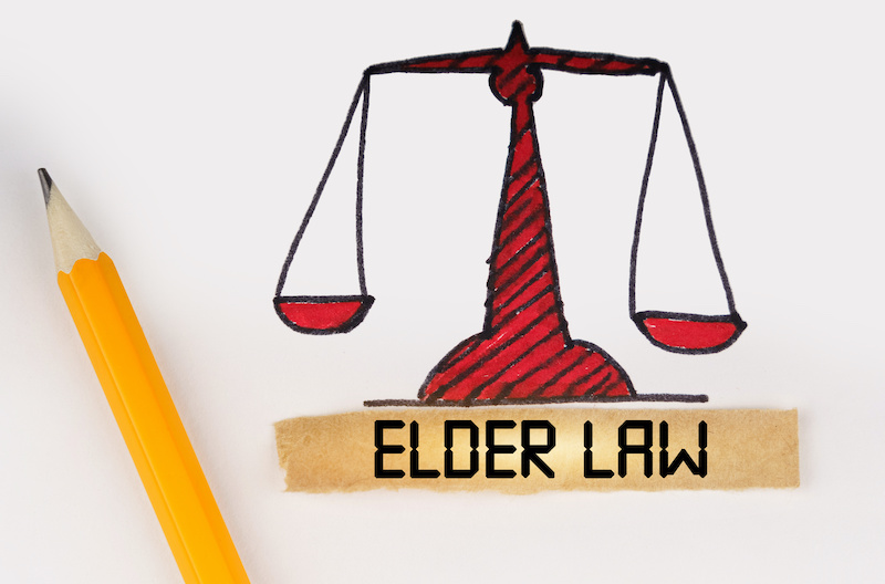 Legal concept. Next to the painted scales of justice lies a pencil and a strip of paper with the inscription - Elder law