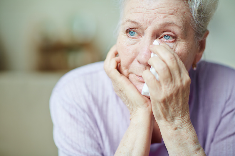 Upset senior woman wiping tears with handkerchief