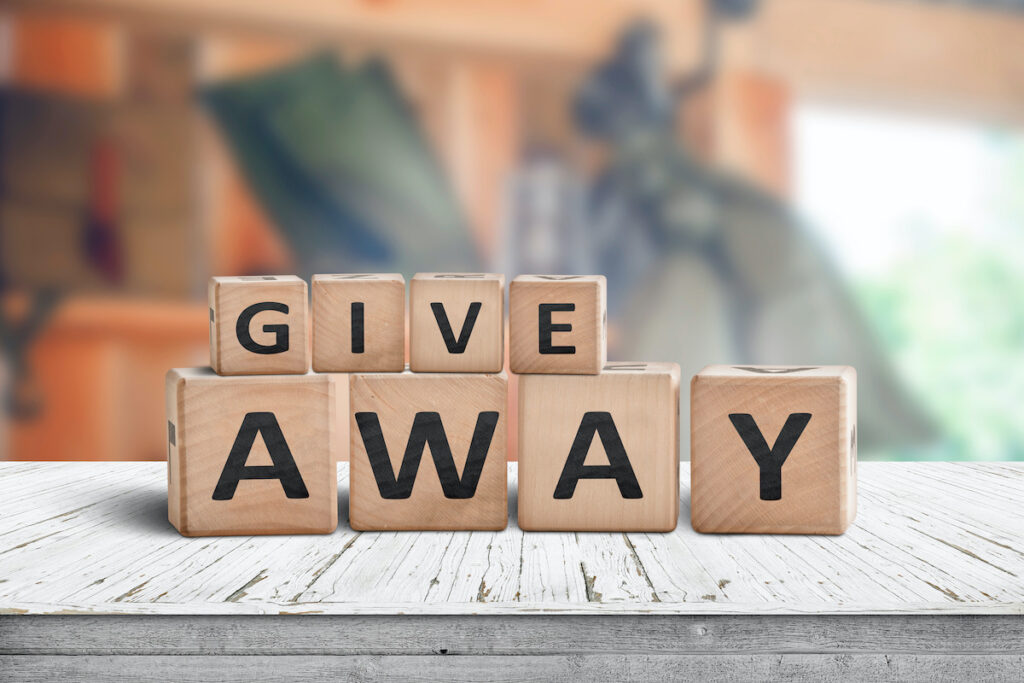 Give away contest sign on a wooden desk with stuff on a blurry background