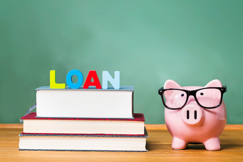 Student loan theme with textbooks and piggy bank and green chalkboard background