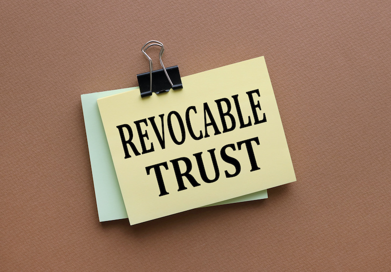Revocable trust text on yellow sticker with clip. on a dark background. brown