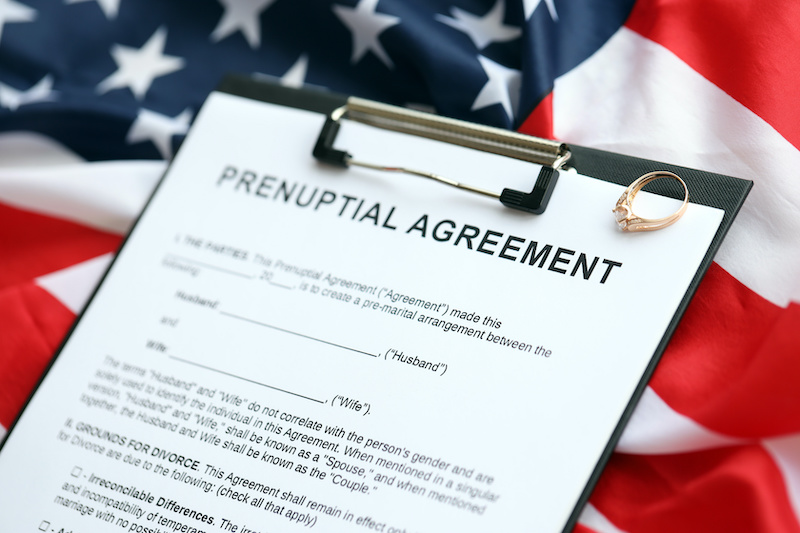 Prenuptial agreement and wedding ring on table. Premarital paperwork process in USA close up