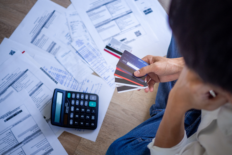 Business people are stressed about credit card debt and many bills on the floor. Men get trouble by calculating monthly expenses and then budgeting not enough money for paying debts.