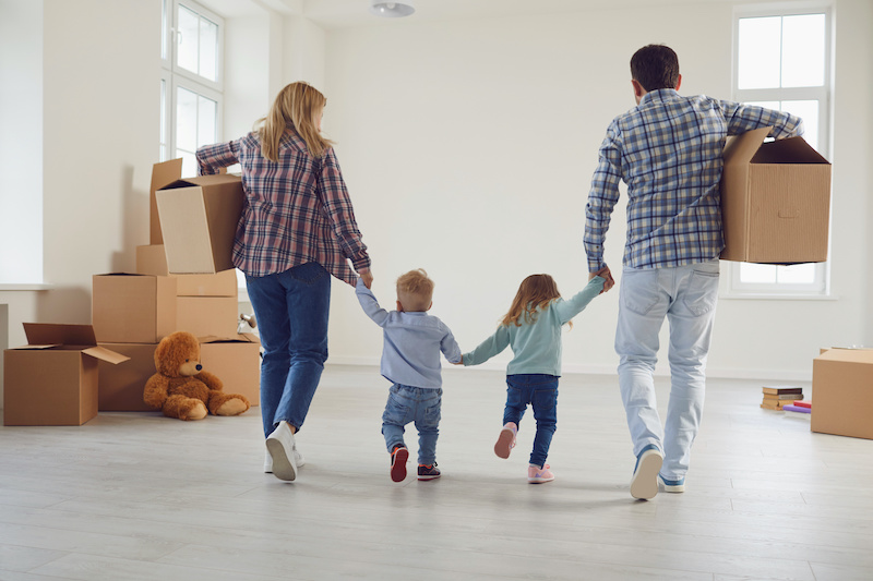 Happy family with children moving with boxes in a new apartment house. Relocation concept new house apartment rental housing.