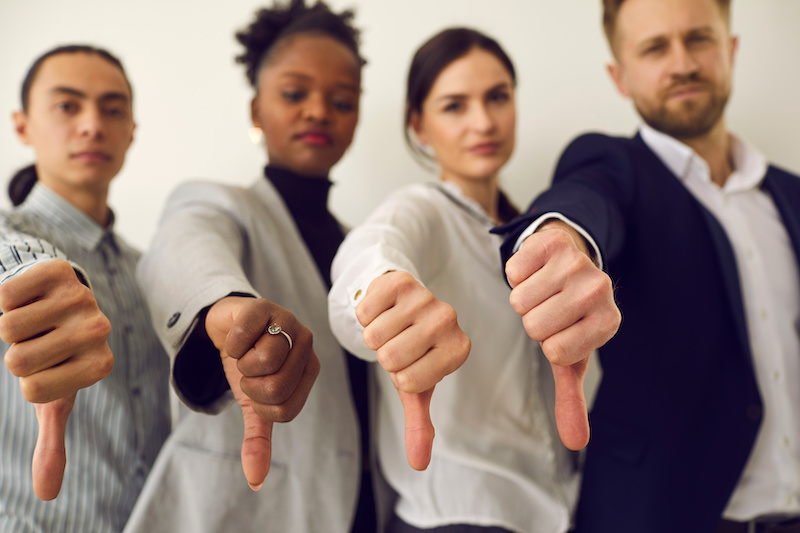 Group of young diverse people giving thumbs down, hands in closeup. Multiracial corporate HR managers saying no and refusing a person. Multiethnic business team showing dislike of bad work