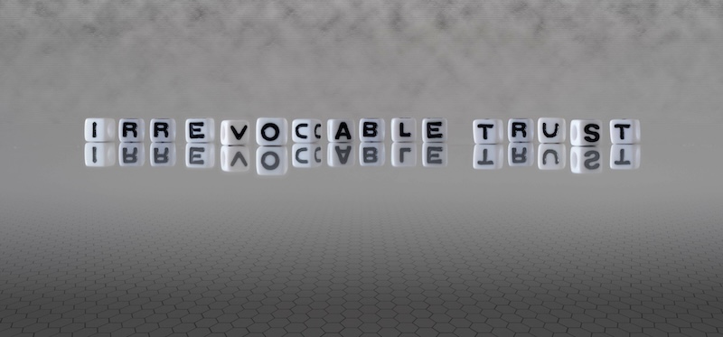 irrevocable trust word or concept represented by black and white letter cubes on a grey horizon background stretching to infinity