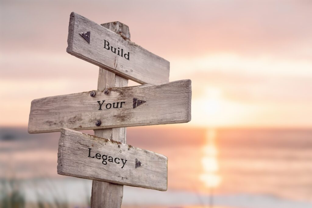 build your legacy text quote written on wooden signpost at the beach during sunset.