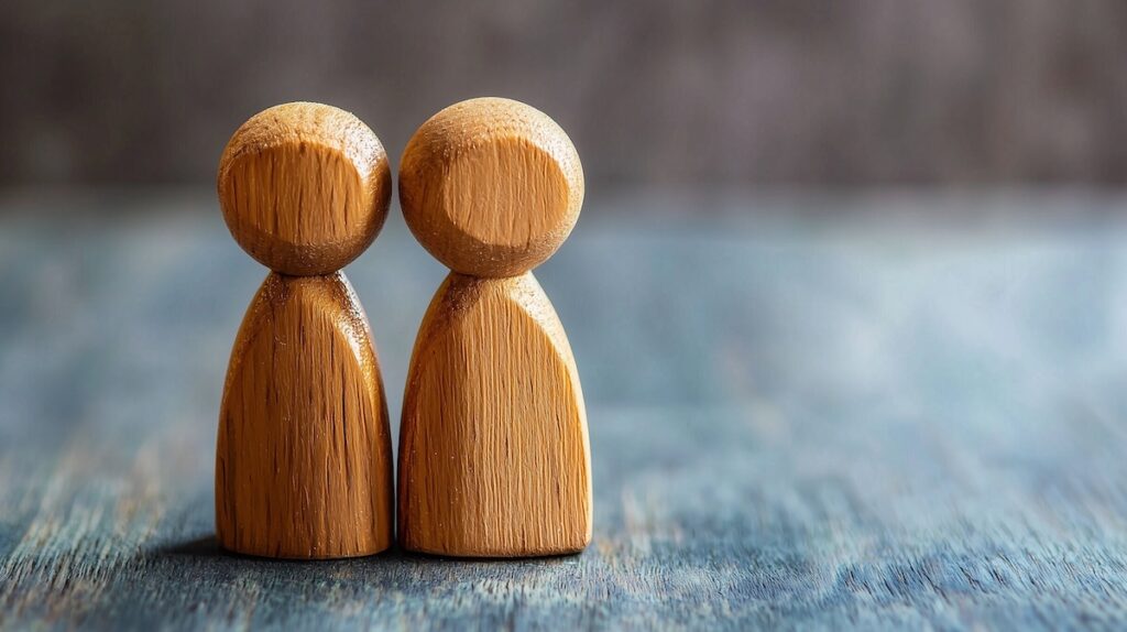 Two wooden figures symbolize unity and connection in marriage counseling.