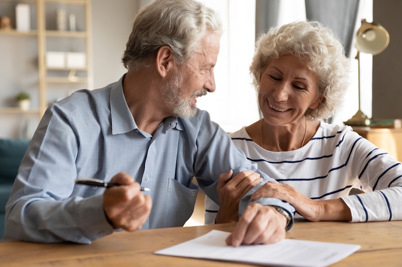 70s couple sit at table indoor discuss agreement term and condition feels satisfied make financial deal ready to sign contract, bequeath savings and property to their children or grandchildren concept