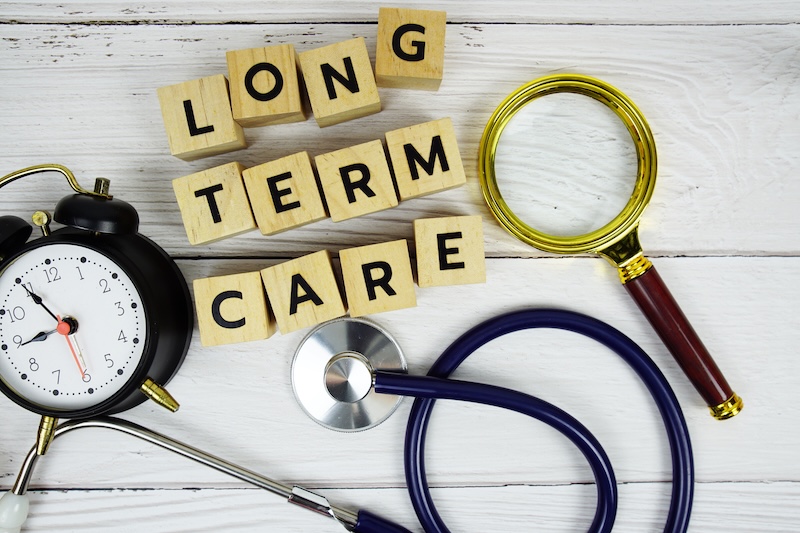 Long term care with wooden blocks alphabet letters and stethoscope on wooden background, Healthy and wellness concept