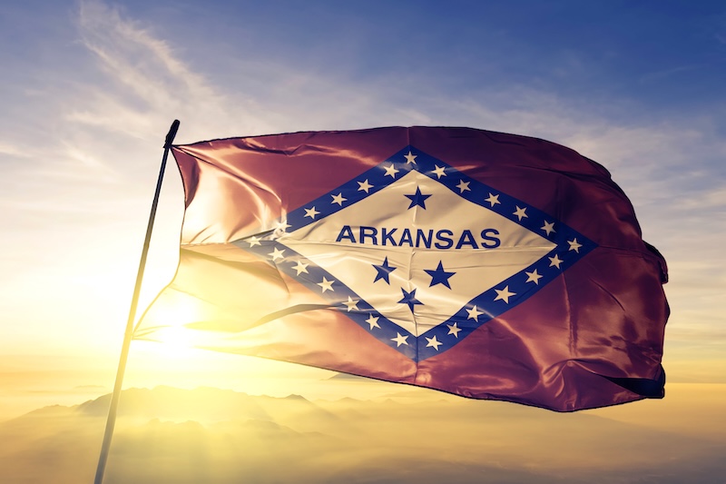 Arkansas state of United States flag textile cloth fabric waving on the top sunrise mist fog