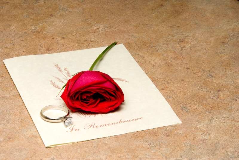 A funeral program with a rose and wedding ring.