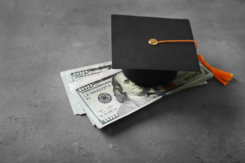 Graduation hat and dollar banknotes on table. Tuition fees concept leaving an inheritance for education