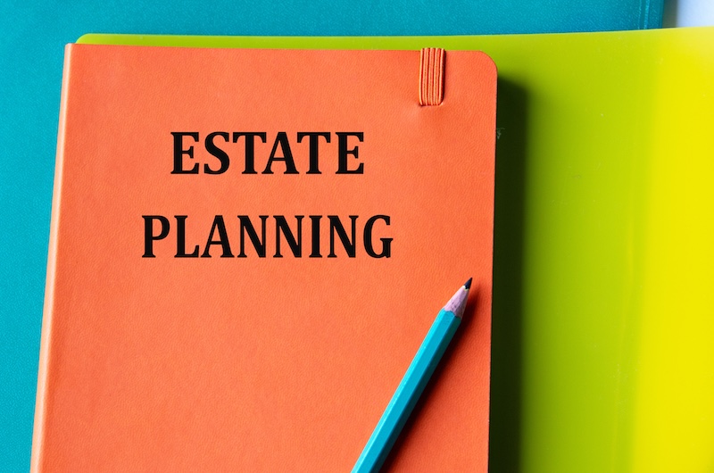 ESTATE PLANNING - words on an orange notepad on a background of multi-colored folders