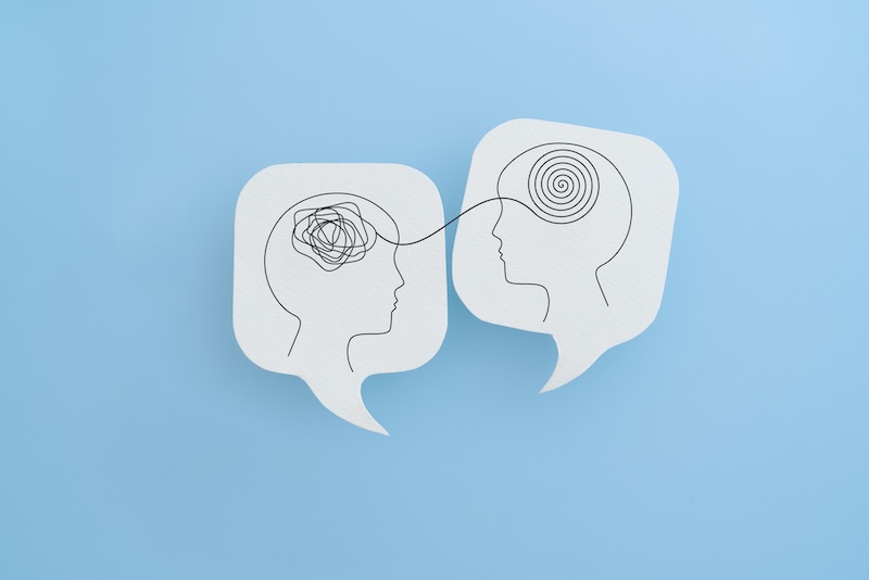 Mental health, brain disorder, World mental health day, Alzheimer, Psychology concept. Human head with Tangle of thoughts and clear line on real white speech bubble paper cut with blue background