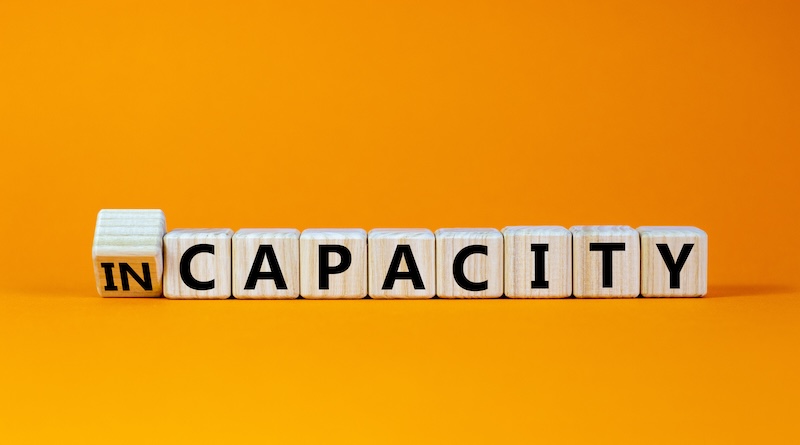 Capacity or incapacity symbol. Turned a wooden cube and changed the word 'incapacity' to 'capacity'. Beautiful orange background. Business and capacity or incapacity concept. Copy space.