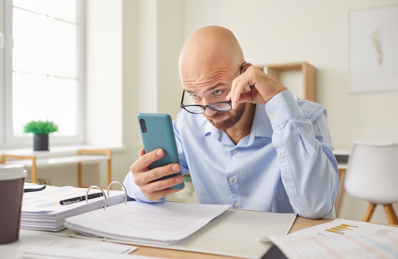 Serious businessman working with phone in office, reading news on a smartphone. Professionals busy schedule, balancing business tasks with staying updated and online on current event clear communication