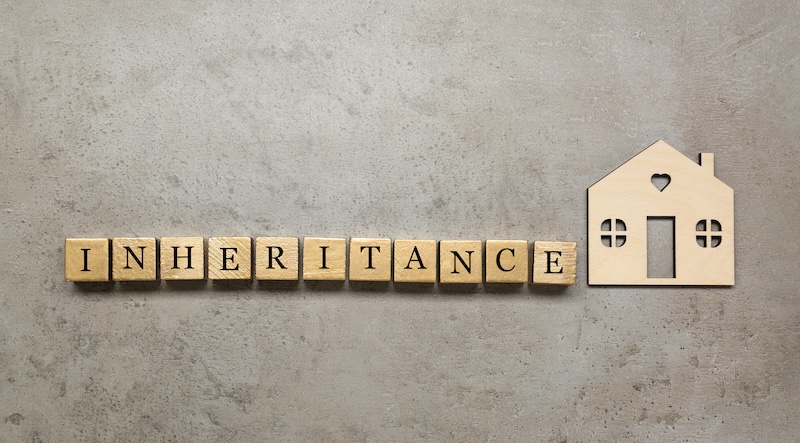 Word Inheritance made with wooden cubes and house model on grey background, flat lay