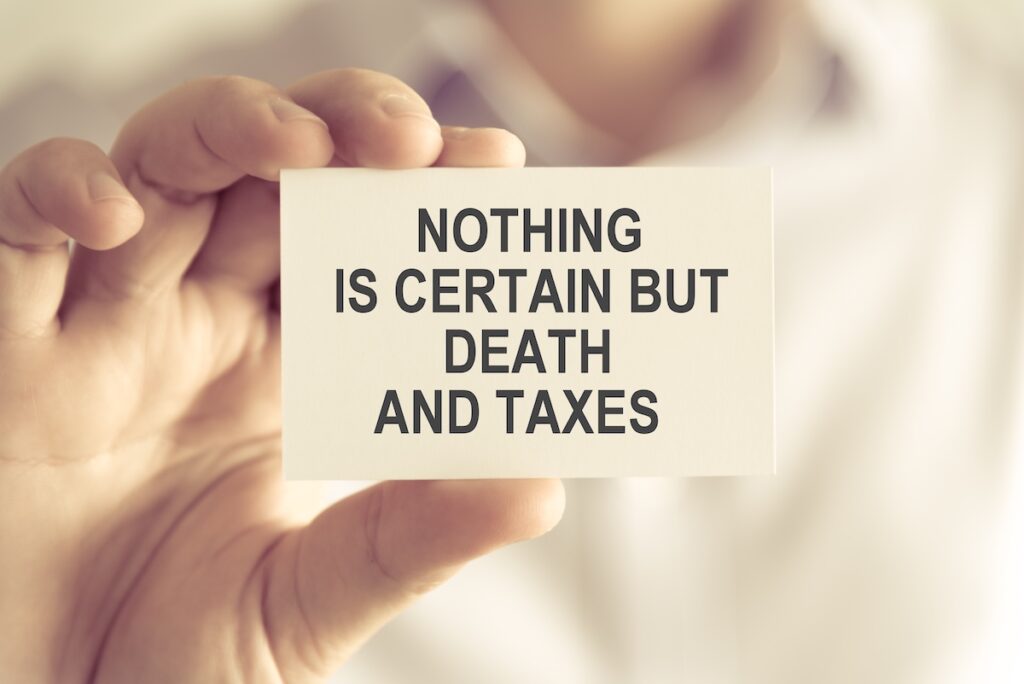 Closeup on businessman holding a card with text NOTHING IS CERTAIN BUT DEATH AND TAXES, business concept image with soft focus background and vintage tone SSUCv3H4sIAAAAAAAEAH1RsW6DMBDdK/UfkOegQDBR6NihW9UhY9ThsC/kGmNXnEkVRfn32hAkD1U33nv3Hn53t+enLBMtMCnxkt0iCpiMGdkP4MnZQBerB4+avBsITCQjd58UwR78yMgx4kEp8NiF2Zl8+Jf/HGacLcIkBkeQxOvIZJF5/UYWrEKxSmZ4bOPMR/uFyrNYlPvqn8A9dZbX+2vfOsN/pb0TKzQGLLoxyZw/Ppfu0KFV16lh0nxAgzA3P8yj4vzjcejTXVxIo0swjJpcspaLU2CioUqSvwdSZLvE5vwJh3TF4UauTwjr/PQSMbcUOtwgwrIqK7mVsmrqXVMUstmI5W5OnUmnbyUdHdBsZIVbnZfVUefyuCvypt00eVurQgLUqpR12NT9F6YVV/o/AgAA