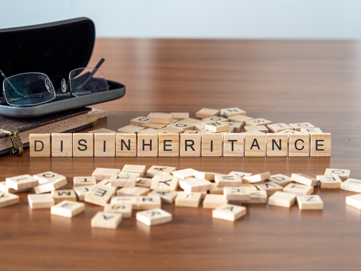 disinheritance word or concept represented by wooden letter tiles on a wooden table with glasses and a book