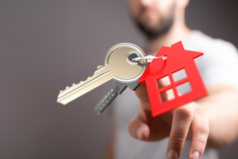 Hand Offering House Key Represents Home Ownership, Real Estate, and Investment