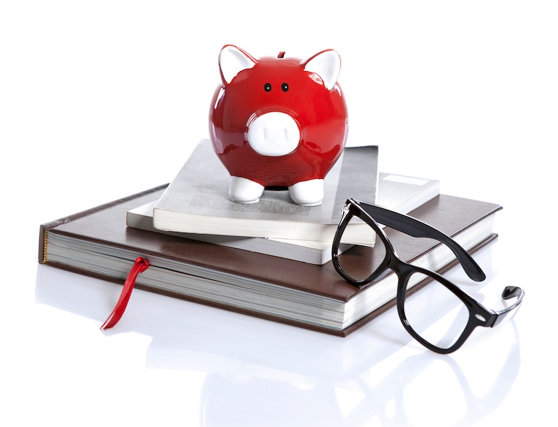 Red piggy bank and glasses with standing on books