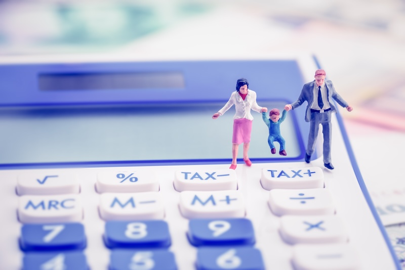 Family tax benefit or FTB / child care fee concept : Couple holds a child on a calculator, depicts a social security payment which is distributed to the parents or guardians of children or teenagers.